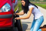 Young woman with a flat tire on car
