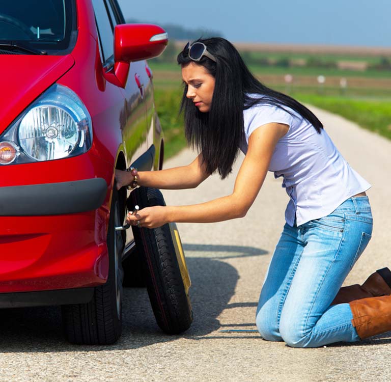 Young woman with a flat tire on car