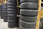 Rows of used tires are organized on wooden shelves in a warehouse