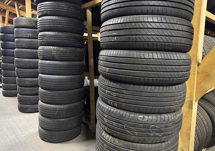 Rows of used tires are organized on wooden shelves in a warehouse
